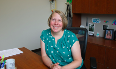 Sara Webb seated at a desk, smiling at the camera.