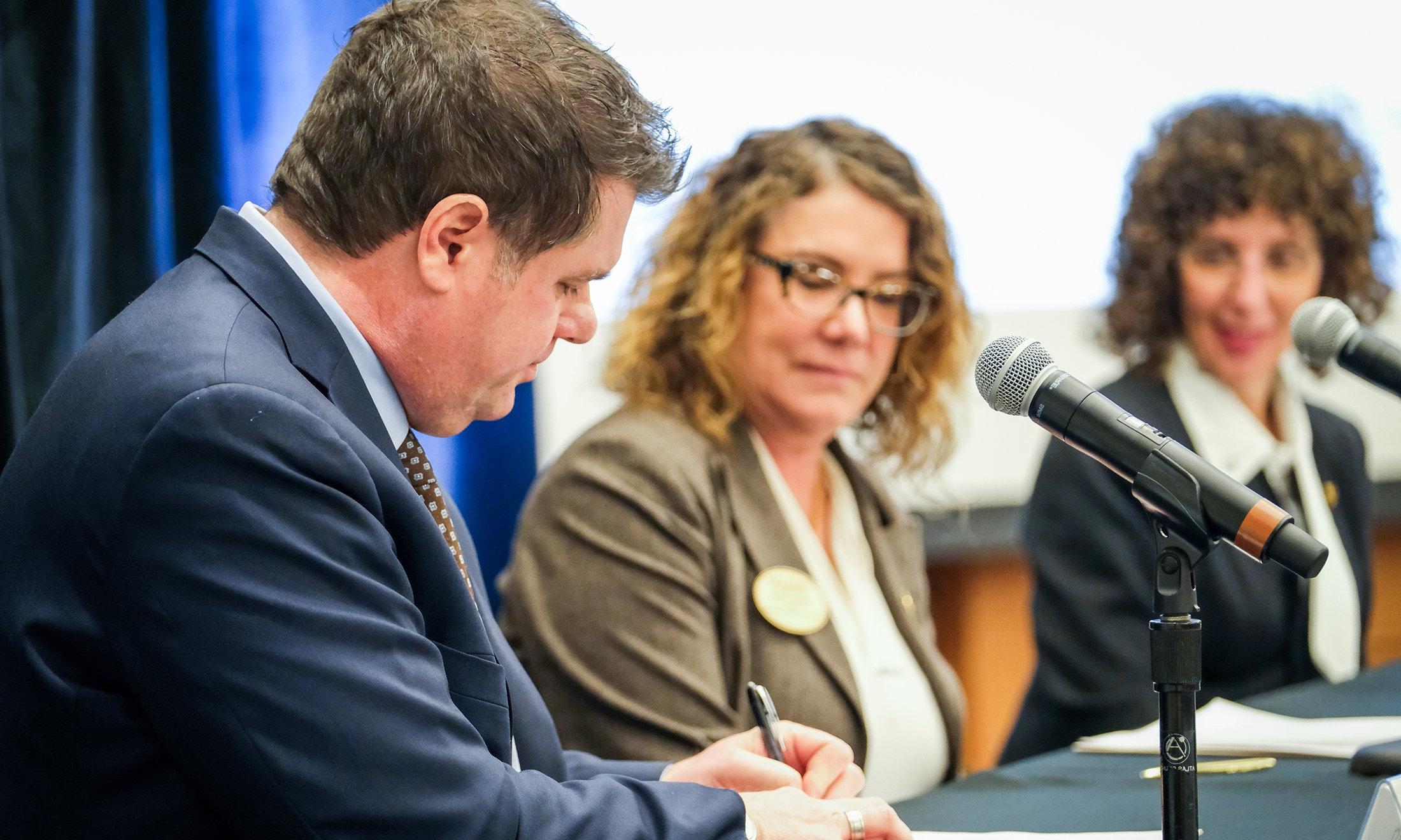 Three people sitting with microphones in front of them