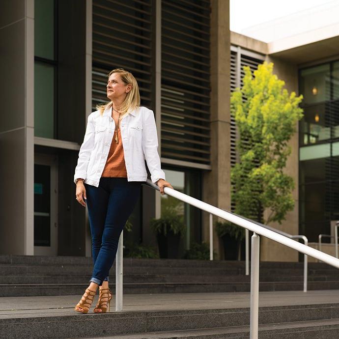 A woman leaning on a hand rail outside of a building.