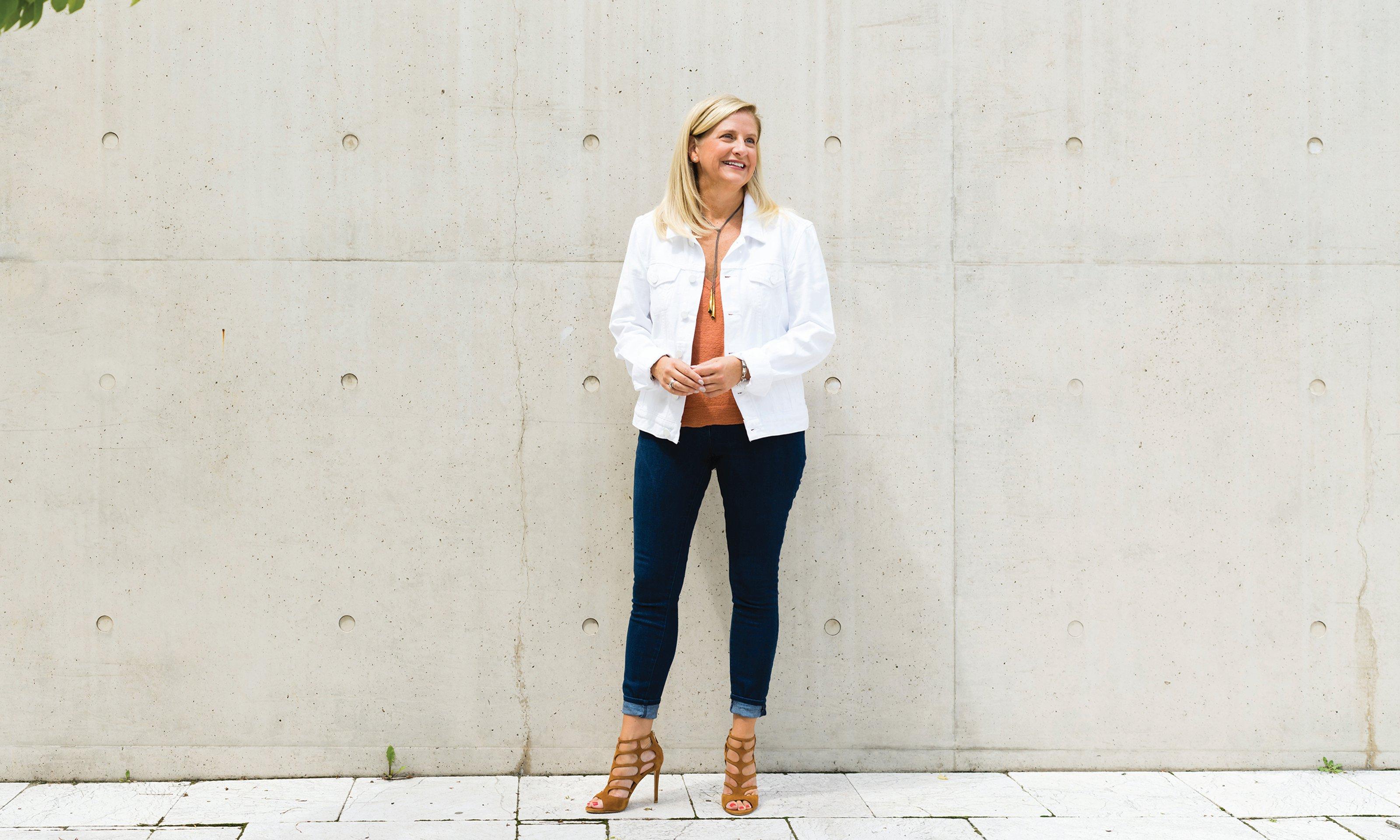 A woman standing in front of a concrete wall.