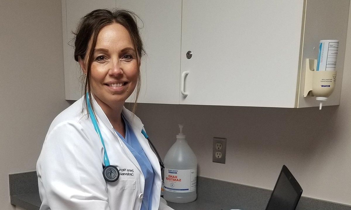 A woman wearing a white lab coat in front of cabinets