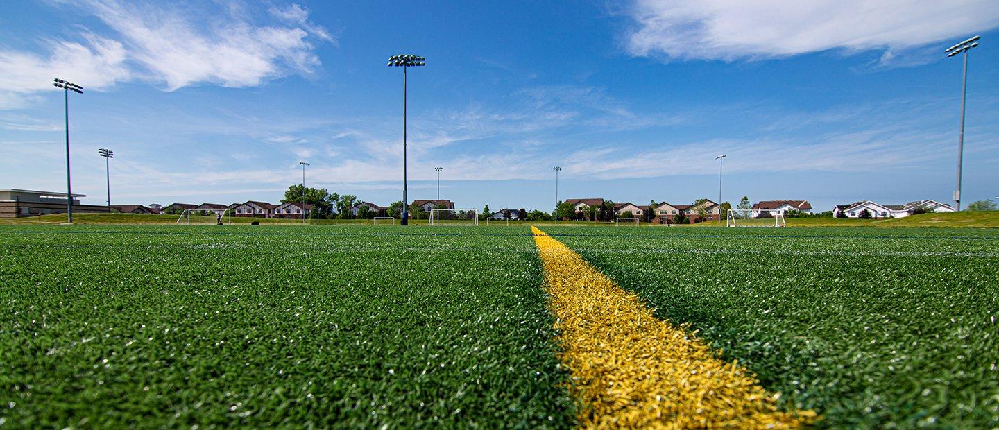 A yellow line painted on a green field at the Outdoor Complex.