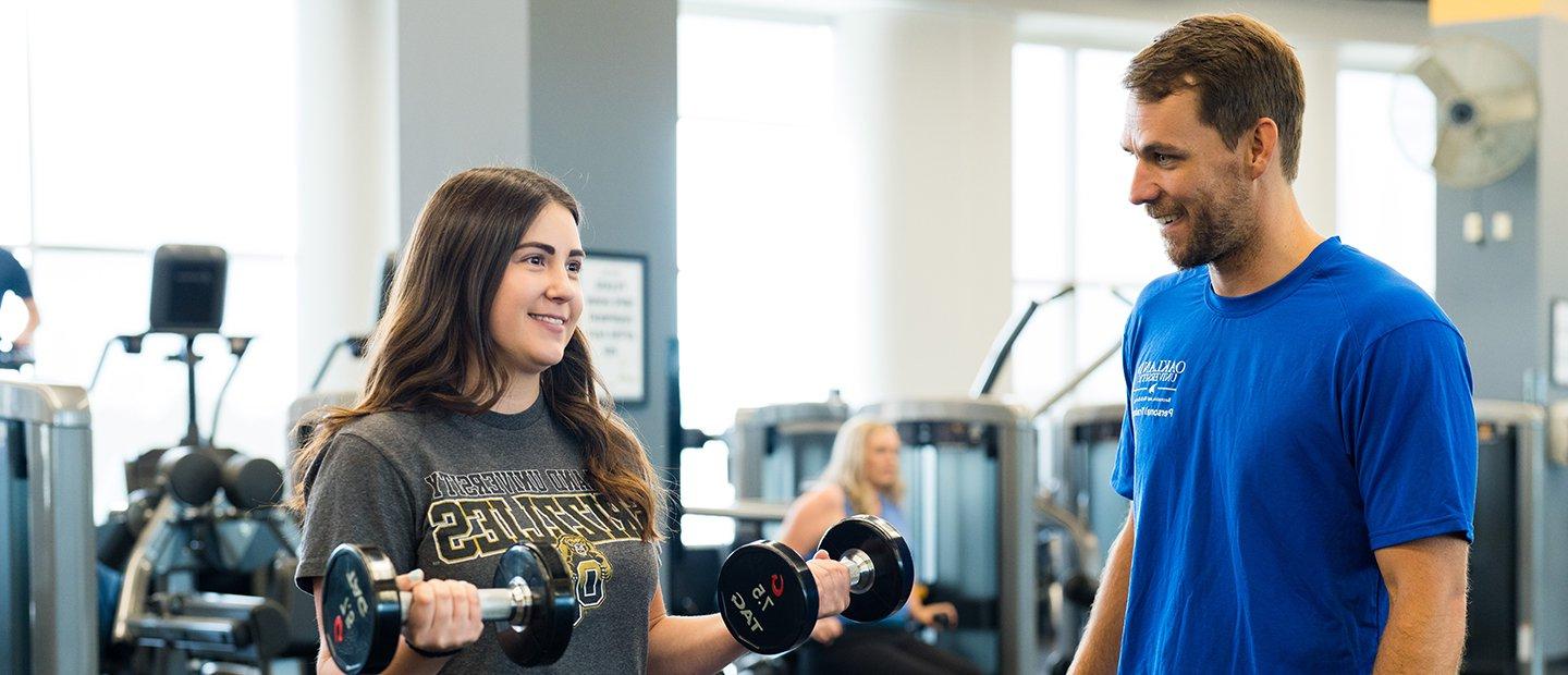 A personal trainer instructing a gym member who is doing bicep curls.